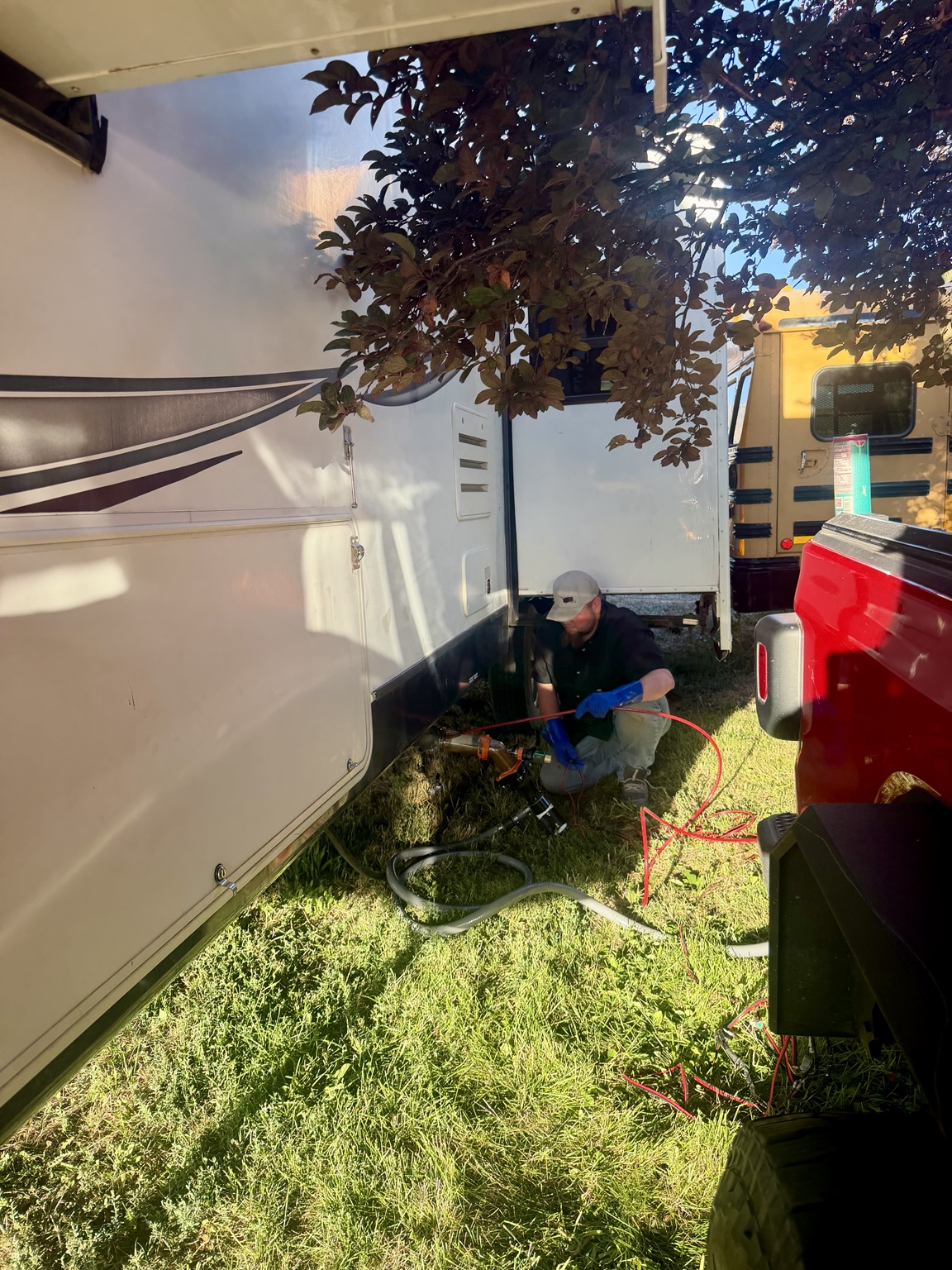 Mobile RV tank cleaning setup beside a fifth wheel